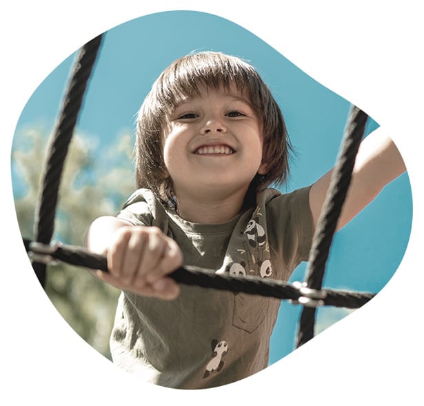 Enfant souriant jouant sur un filet d’escalade en plein air
