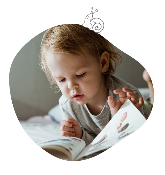 Petit enfant concentré en train de lire un livre illustré
