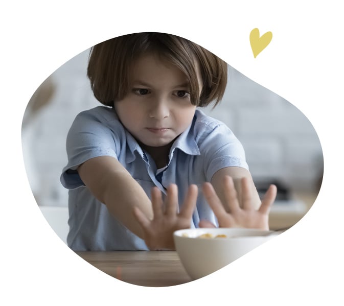Enfant repoussant un bol de nourriture sur une table