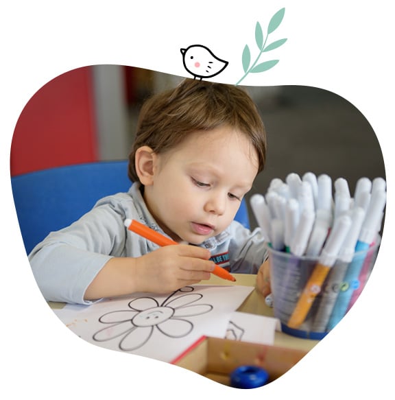 Jeune garçon qui dessine avec un feutre orange sur une feuille et une représentation de fleur