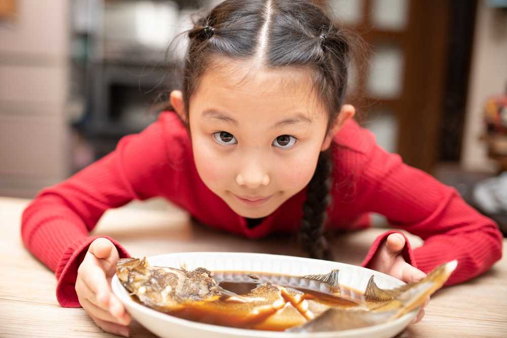Enfant qui mange du poisson gras, source en oméga-3 DHA et EPA
